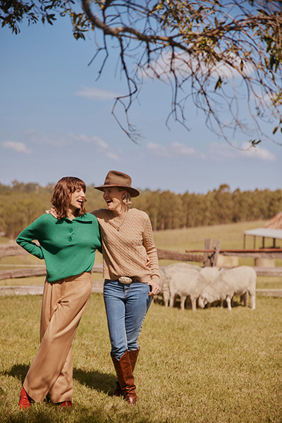 2 women wearing Sportscraft clothing in a paddock with sheep behind
