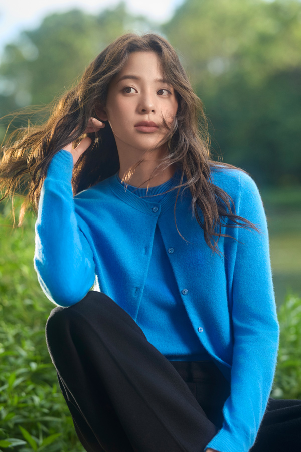Woman wearing beige merino wool jacket and wide-leg trousers walking in a park